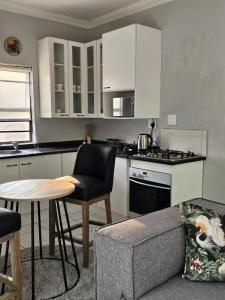 a kitchen with white cabinets and a table and a chair at Lanina Self Catering Apartments in Johannesburg