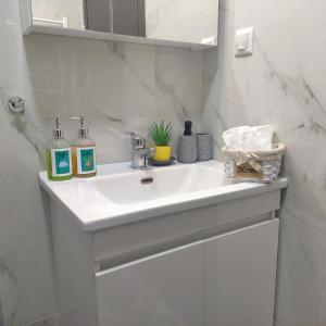 un lavandino bianco nel bagno con due bottiglie di sapone di Delta - Central Elegant Apartment a Kateríni