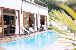 une maison avec une piscine et deux chaises longues dans l'établissement Nai, à Praia de Santiago