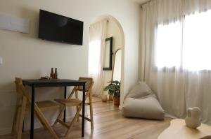 a living room with a table and a television on a wall at Vanilla! 1 Bedroom Apartment in Puerto de la Cruz +9 photos