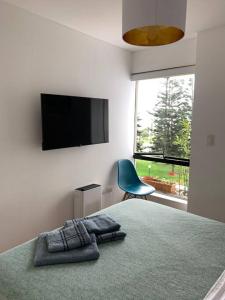 een slaapkamer met een bed, een televisie en een stoel bij Apartamento frente al mar in Lima
