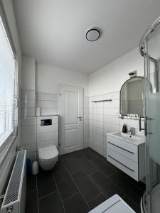 Baño blanco con aseo y lavamanos en Haus Ostseestrand36, en Timmendorfer Strand