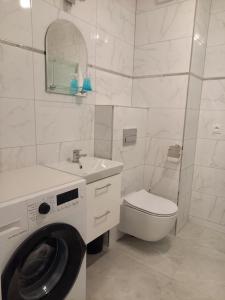 biała łazienka z pralką i toaletą w obiekcie Apartament na Górnej 22 z parkingiem podziemnym w Kielcach
