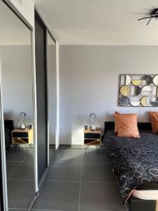 een slaapkamer met een bed, 2 tafels en een spiegel bij Joli appartement résidence neuve in Saint-Mandrier-sur-Mer