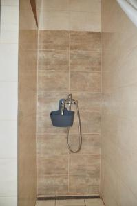 una ducha con cubo en una pared de azulejos en Néró Apartman, en Veľký Meder
