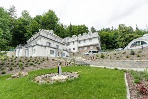 an exterior view of a large white building on a hill at Leśna Polana- blisko centrum, Mini Spa, cicha, spokojna okolica, parking gratis in Krynica Zdrój