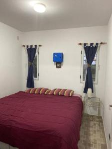 a bedroom with a red bed with blue curtains at Hostal del Sol - Fisherton in Rosario