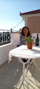 una mujer sentada en una mesa en un balcón en Helena Inn, en Svoronata
