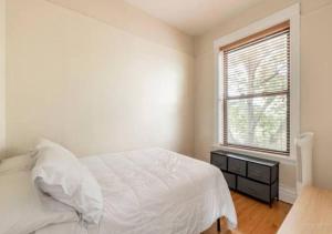 a white bedroom with a bed and a window at The Roscoe Village Guesthouse in Chicago