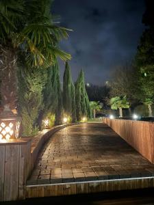 a cobblestone street at night with a fence and trees at La tanière de Bonneville in Bonneville-sur-Touques