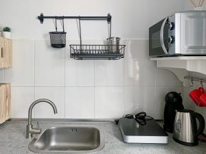 a kitchen with a sink and a microwave at Habitaciones privadas cerca de la playa y aeropuerto en casa compartida con otros huéspedes in Playa Honda