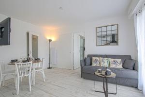 Una sala de estar con un sofá, una mesa y sillas. en L'idéal à Blonville, en Blonville-sur-Mer