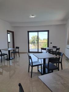 una stanza con tavoli e sedie e una grande finestra di Villa Corina a Vaccarizzo Albanese