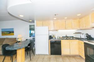 une cuisine avec une table et un réfrigérateur blanc dans l'établissement Ilikai Tower 1936 condo, à Honolulu