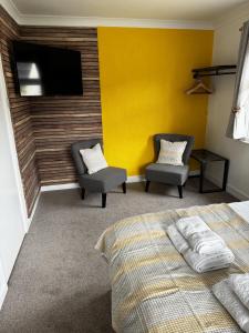 a bedroom with a bed and two chairs and a tv at Watermead House in Chard