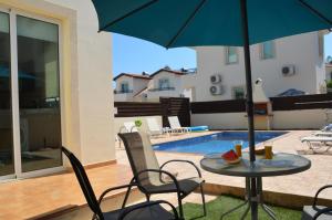 a patio with a table and chairs and an umbrella at Villa millie Cyprus in Protaras