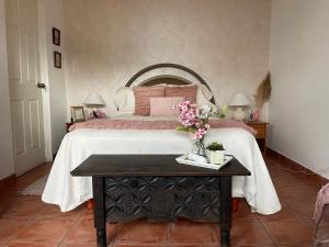 a bedroom with a bed with a table with flowers on it at Autumn in Antigua Boutique Hotel in Antigua Guatemala