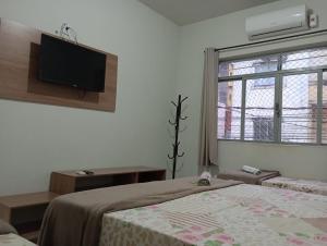 a bedroom with two beds and a flat screen tv at Pousada Divina Fé in Aparecida