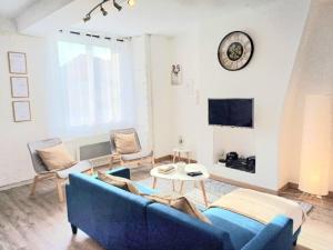 La Belle Du Thil - Spacieuse - Proche Aéroport في بوفيه: غرفة معيشة مع أريكة زرقاء وساعة على الحائط