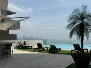 um grupo de pessoas sentadas em cadeiras ao lado de uma piscina em Apartamento en Panama y Punta Pacífica, Céntrico y Costa de Panamá na Cidade do Panamá