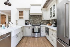 a kitchen with white cabinets and a stainless steel refrigerator at Exquisite luxury executive cottages in Woodside