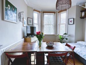 - une salle à manger avec une table, des chaises et un lit dans l'établissement Stylish Flat with Artistic Flair in Central London, à Londres