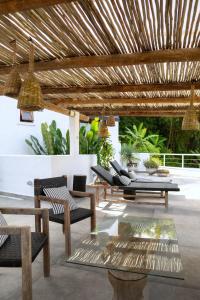 patio z krzesłami i stołami oraz drewnianą pergolą w obiekcie Nai w mieście Praia de Santiago