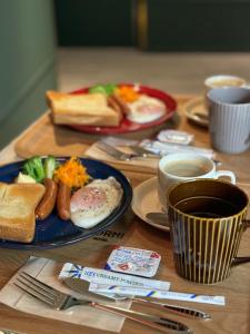 einen Holztisch mit Frühstücksteller und Kaffee in der Unterkunft Hotel Torni ホテル トルニ in Toyama