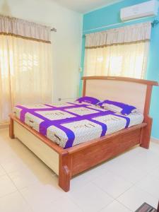 a bed with a purple and white comforter in a room at Coquet appart in Abomey-Calavi