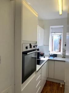 a kitchen with white cabinets and a black oven at Cozy Entire Flat walking to Hyde Park in London