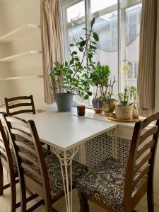 a dining room table with chairs and potted plants at Cozy Entire Flat walking to Hyde Park in London