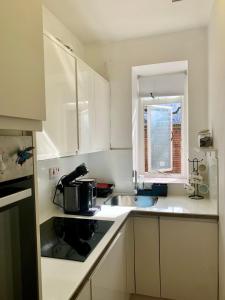 a white kitchen with a sink and a stove at Cozy Entire Flat walking to Hyde Park in London