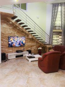 a living room with a couch and a tv and stairs at Coquet appart in Abomey-Calavi