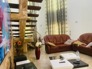 a living room with two couches and a staircase at Coquet appart in Abomey-Calavi