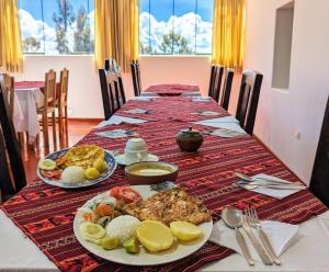 una mesa larga con platos de comida. en Amantani sol Andino en Ocosuyo
