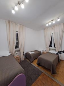 1 dormitorio con 2 camas y 2 ventanas en Rome Apartment D'Amata, en Ciampino
