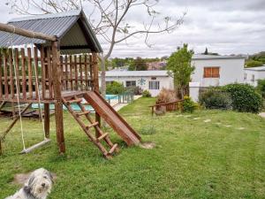 a dog sitting in the grass next to a wooden swing at La Enramada in Victoria