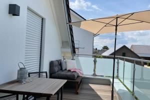 a balcony with a table and a couch and an umbrella at Ferienwohnung - nah an Phantasialand, Köln & Bonn in Weilerswist