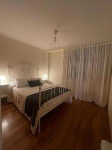 um quarto com uma cama e uma janela com cortinas brancas em Apartamento con encanto en Cuntis em Cuntis