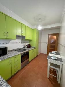 uma cozinha com armários verde lima e uma mesa em Apartamento con encanto en Cuntis em Cuntis