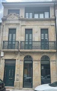 um edifício de pedra com uma varanda, portas e janelas em Apartamento con encanto en Cuntis em Cuntis