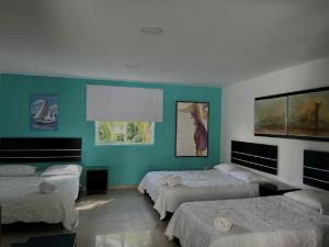 um quarto com 3 camas e paredes azuis em Villa San Miguel em San Andrés