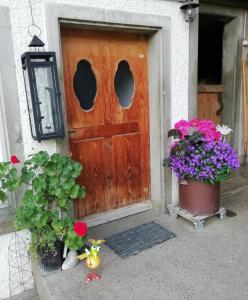 une porte en bois avec deux plantes en pot et des fleurs dans l'établissement Emmental Ferien, à Langnau im Emmental