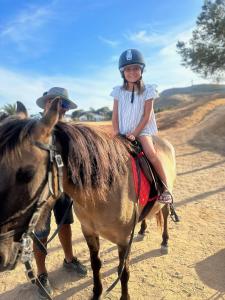 a little girl riding on a horse with a man at Profetas GuestHouse in Porto Santo