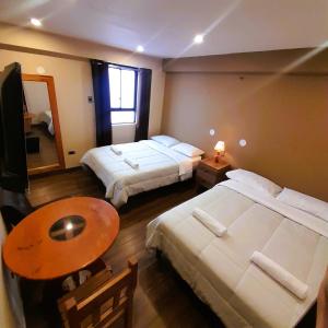 una camera d'albergo con due letti e un tavolo di LAGUNA HOUSE a Huaraz