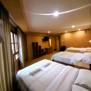 a hotel room with three beds and a television at Laguna House in Huaraz
