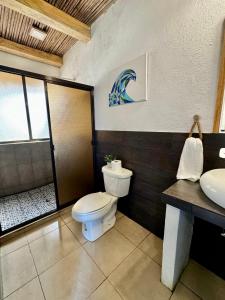 y baño con aseo, ducha y lavamanos. en Miravalle Eco Surf, en Sonsonate