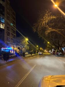 an empty street at night with cars parked in a parking lot at Temali Apartment in Shkodër