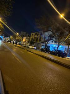 Una calle de la ciudad por la noche con coches aparcados en la calle en Temali Apartment, en Shkodër