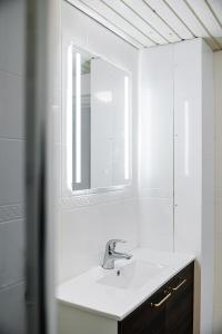 a white bathroom with a sink and a mirror at Ydinkeskustan designkaksio in Hämeenlinna